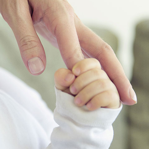 Baby-Hand hält Finger einer Frau. 